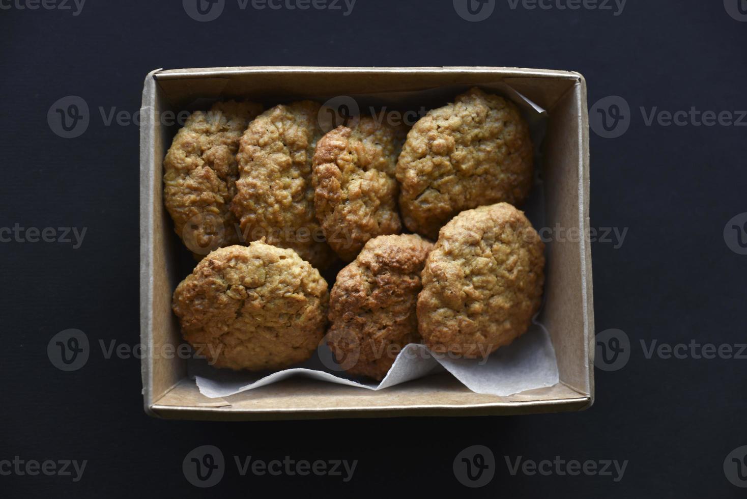 Delicious oatmeal cookies in a cardboard box on a black background. Sweet cookies. A sweet snack for tea. photo