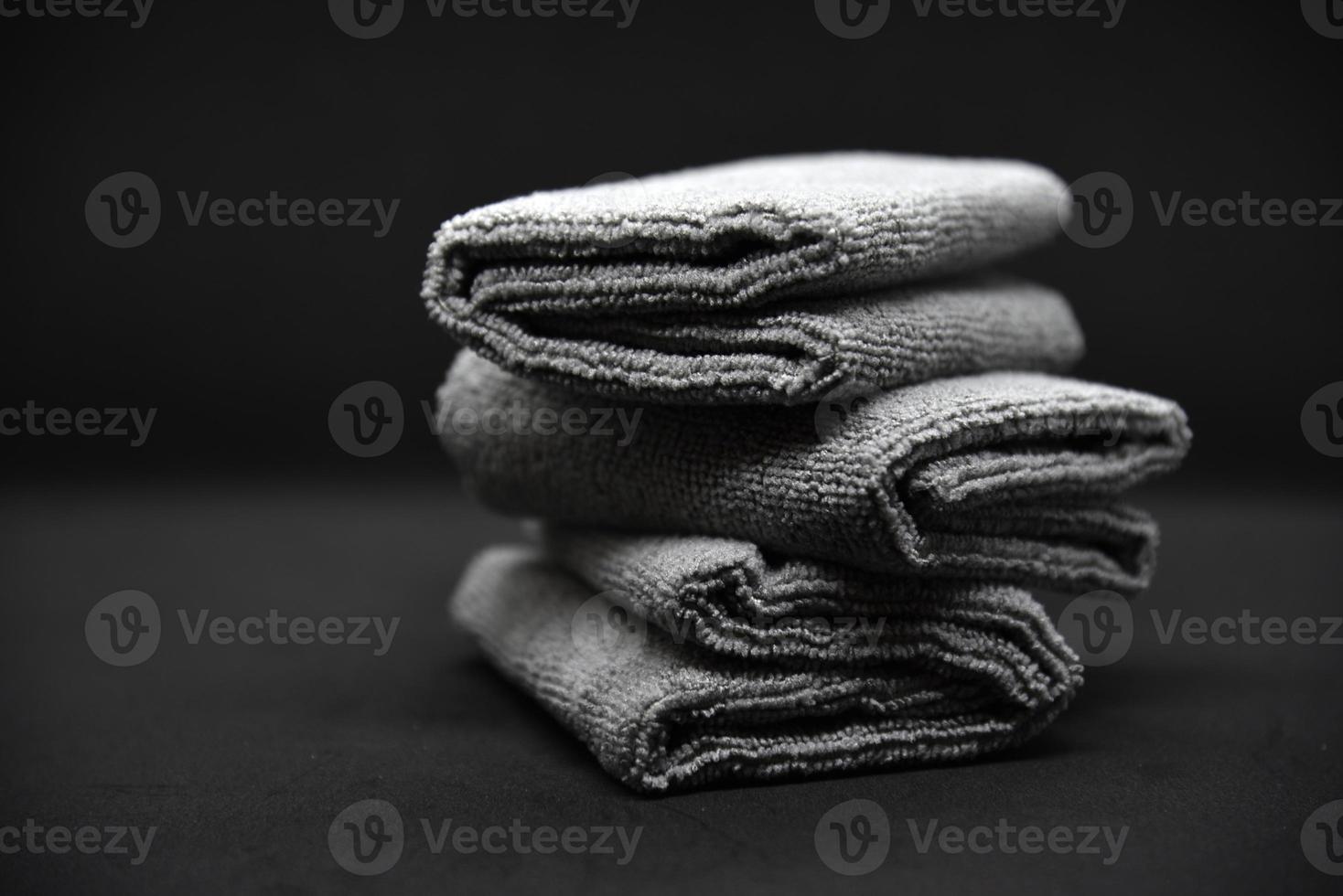 Three gray towels on a black background. Terry cloths for wiping furniture. Towels on a black background. photo