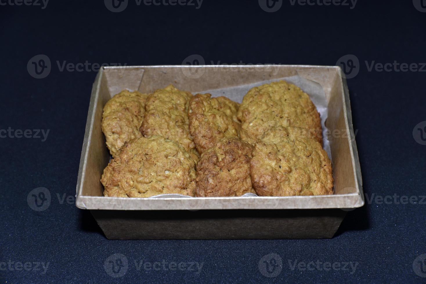 Delicious oatmeal cookies in a cardboard box on a black background. Sweet cookies. A sweet snack for tea. photo