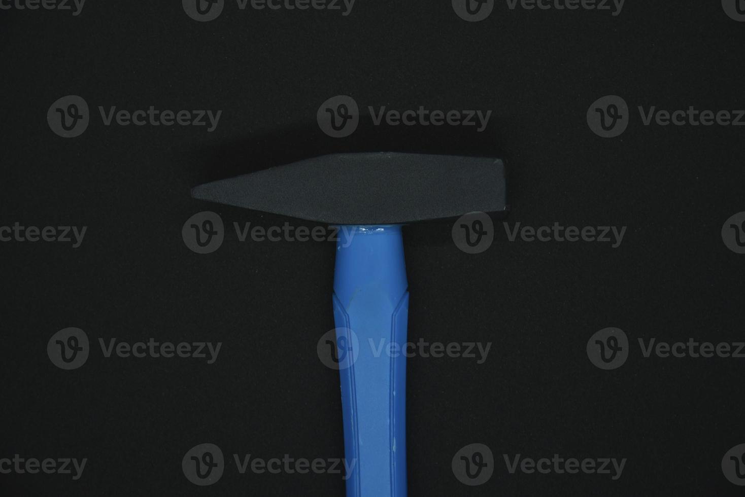 Construction hammer on a black background. A carpenter's hammer with a blue handle on a black background. photo