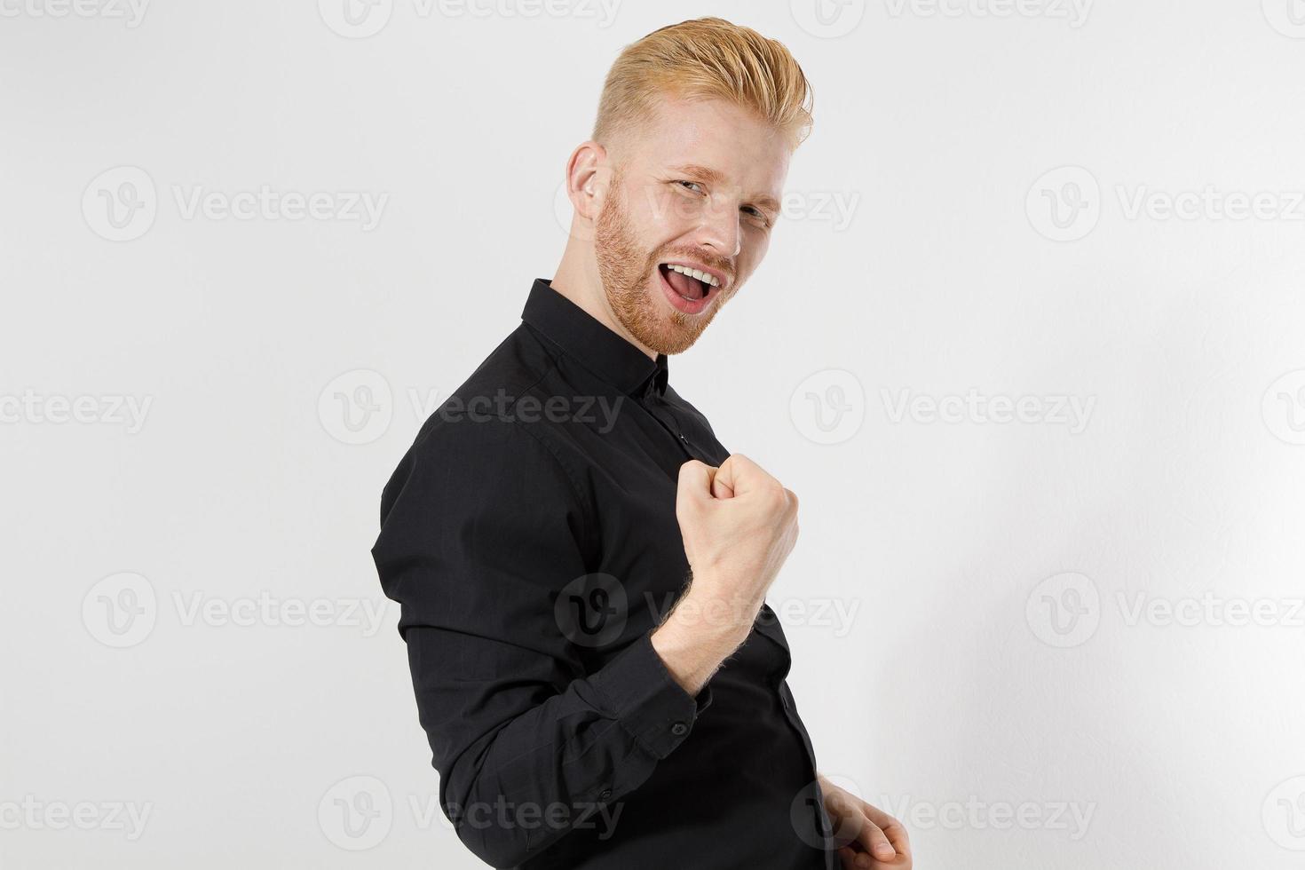 Reach the goal concept. Happy excited shock young guy entrepreneur isolated on gray background. Copy space. Close up Successful Redheaded man with red beard in stylish black shirt. Positive smart male photo