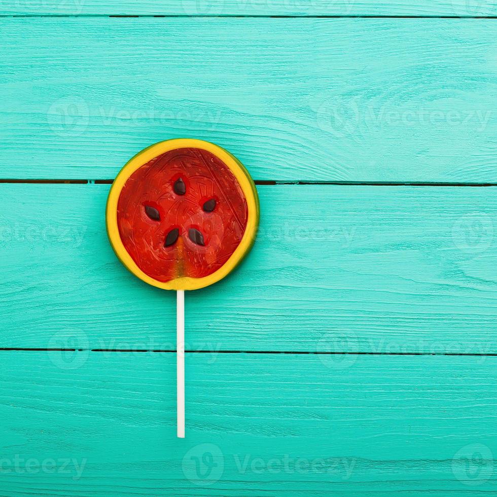 comida de caramelo de verano de sandía sobre fondo de madera azul. vista superior. Bosquejo. copie el espacio. piruleta dulce foto