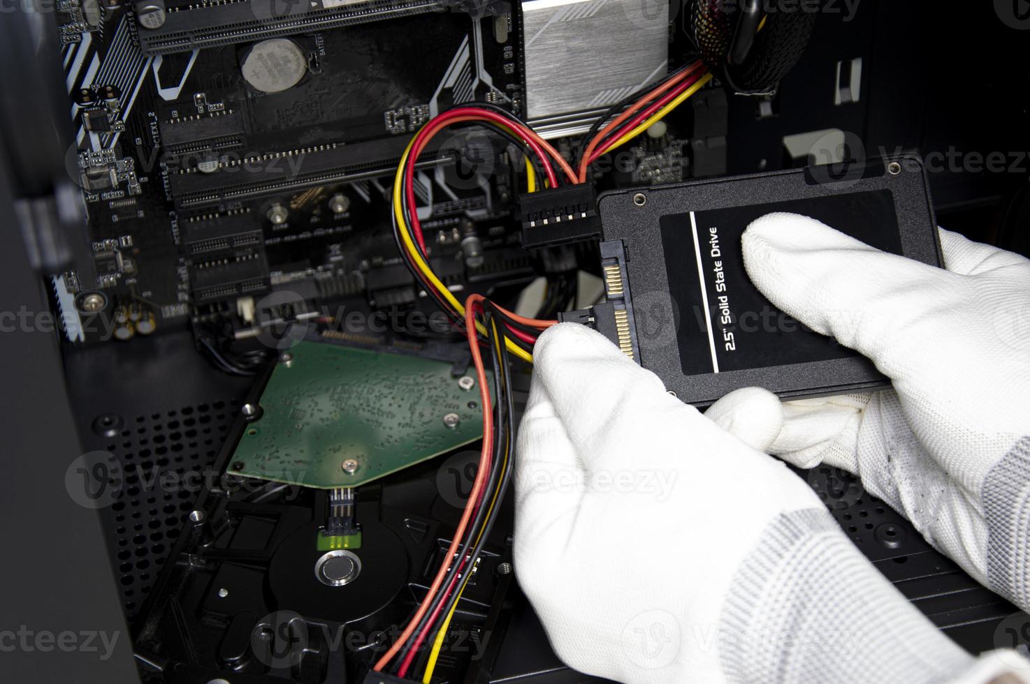 The mechanic is connecting the wires to the 2.5 inch SSD hard drive. photo