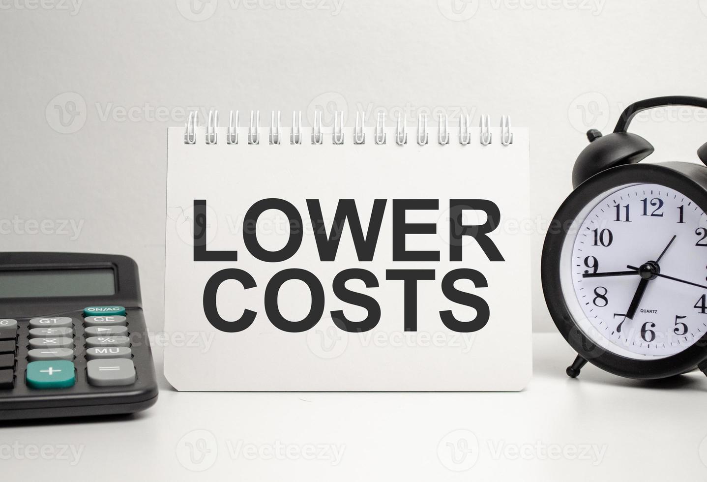 lOWER COSTS words with calculator and clock with notebook photo