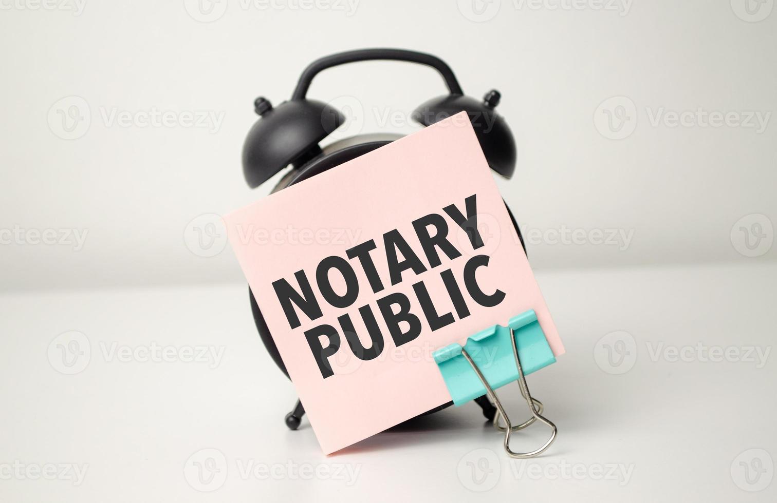 alarm clock with pink sticker with the text NOTARY PUBLIC. photo