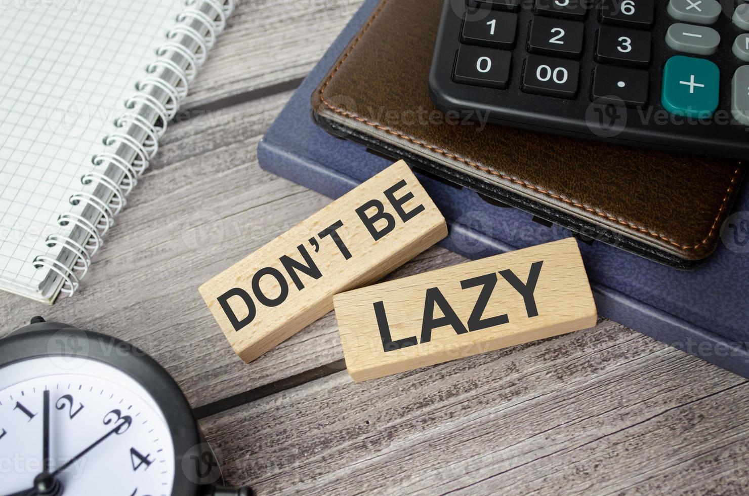 alarm clock, calculator, notebook and wooden blocks with the inscription - don't be lazy photo