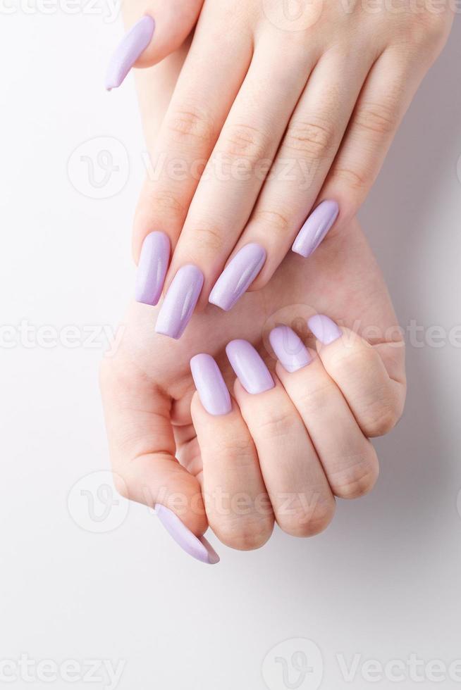 manos de una chica con una manicura violeta suave sobre un fondo blanco. foto