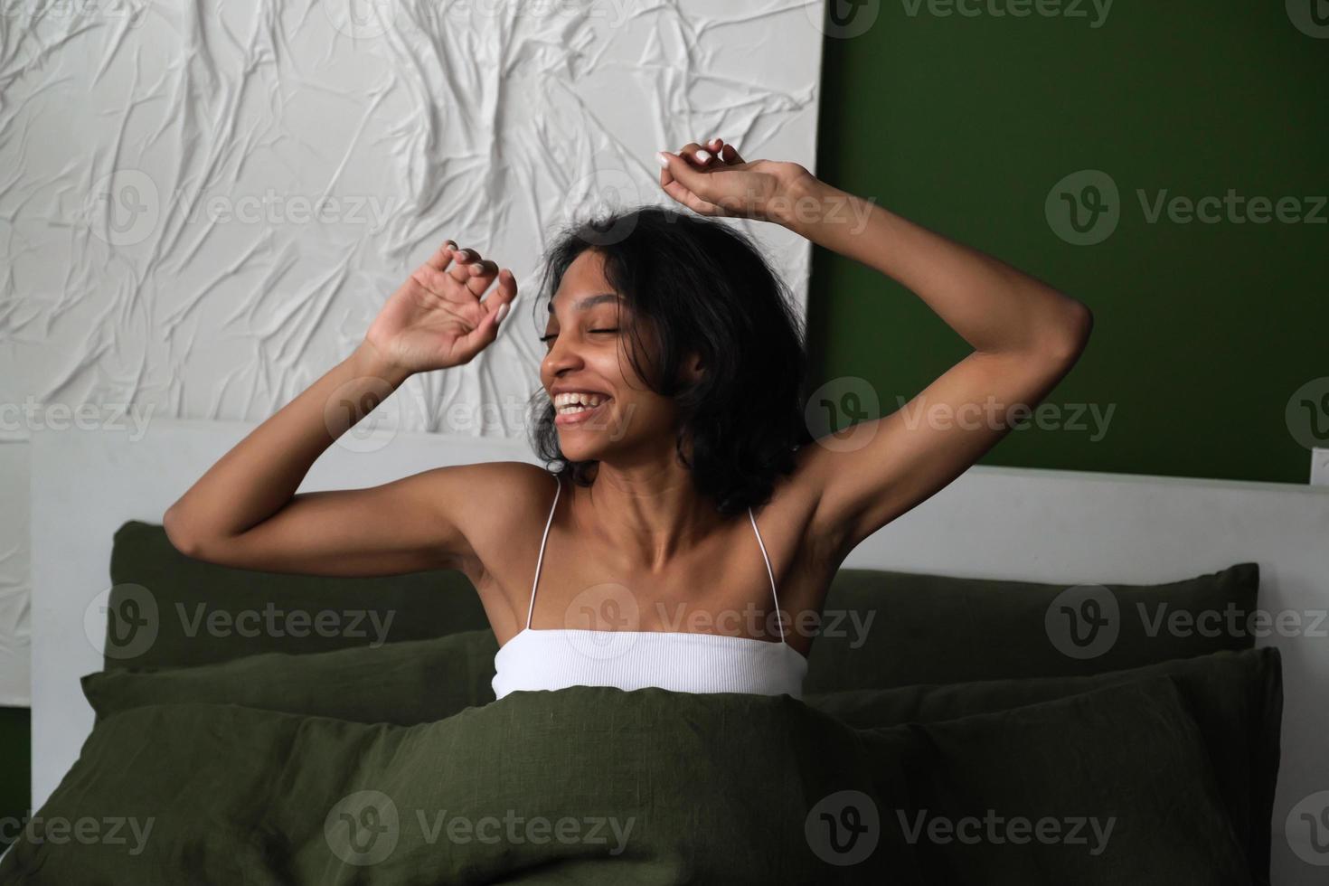 feliz mujer afroamericana despertando en su cama. buenos días, buen concepto de sueño foto