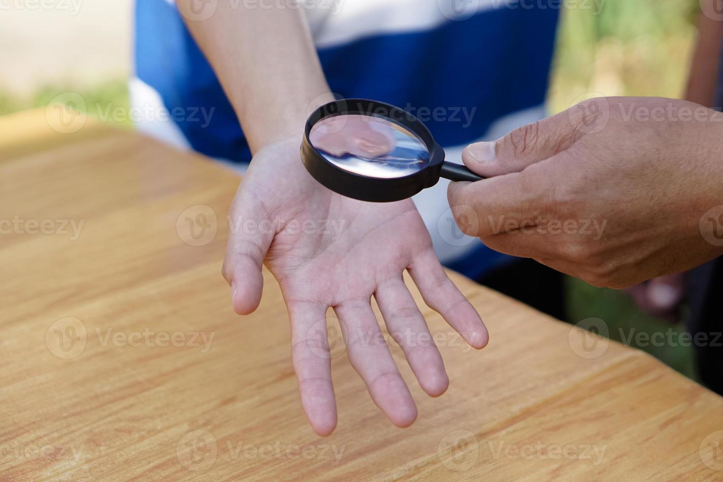 la mano de primer plano sostiene una lupa para inspeccionar las líneas de la palma. concepto, quiromancia, astrología. adivinación, misterio, magia, fortuna, destino. predicción para la vida futura, eventos. predicción palmista. foto