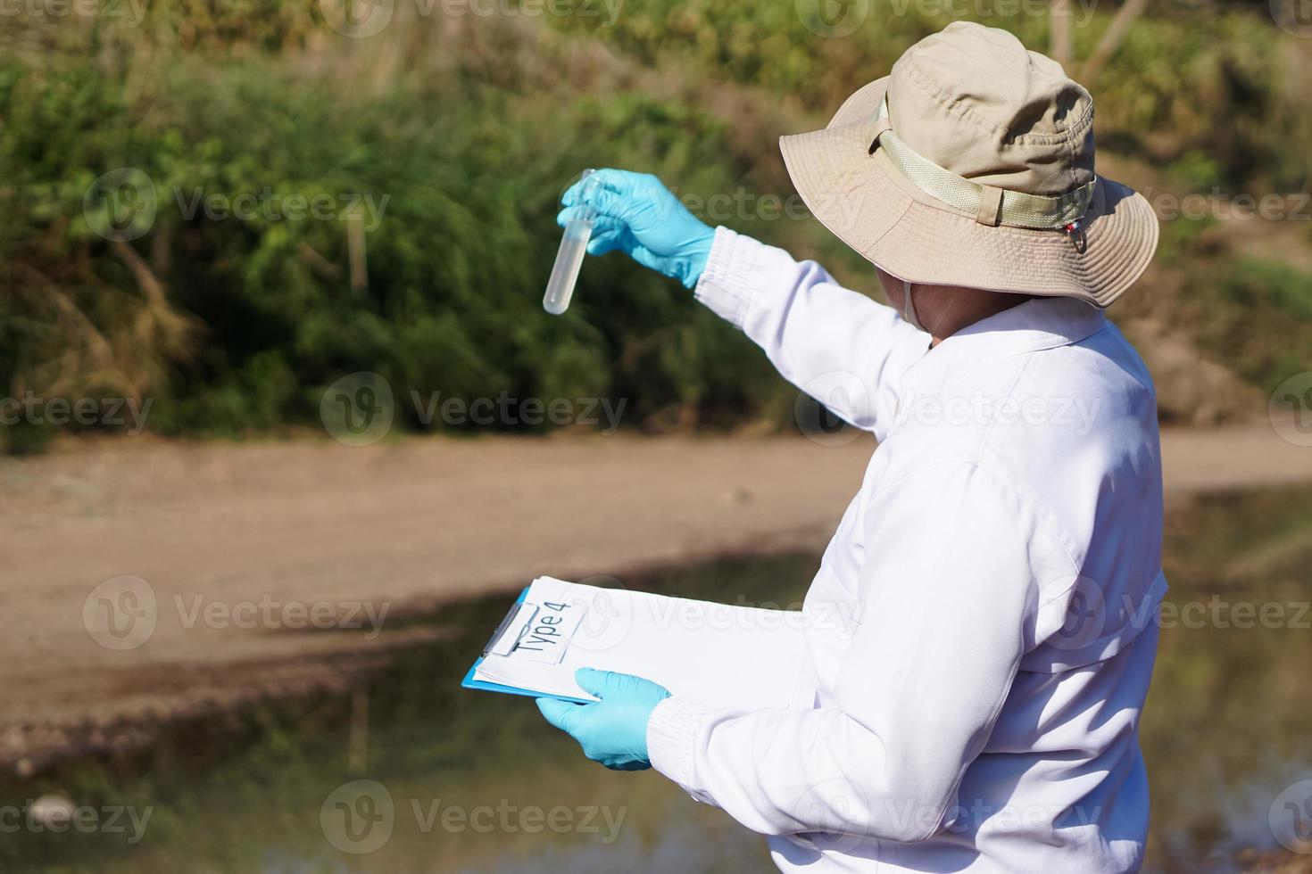 Asian man environment researcher holds tube of sample water to inspect from the lake. Concept, explore, analysis water quality from natural source. Ecology field research. photo