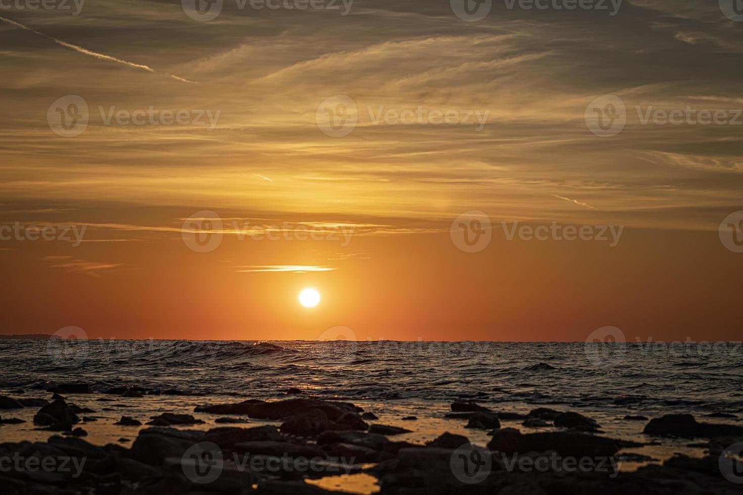 impresionante paisaje marino matutino con sol y piedras en el agua foto