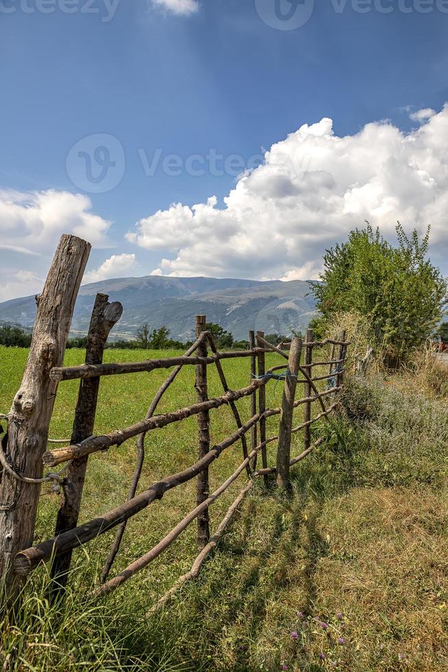 una cerca de madera hecha a mano hecha de varillas delgadas. la antigua valla de troncos de árboles, paisaje rural, fondo de papel pintado de la naturaleza. foto