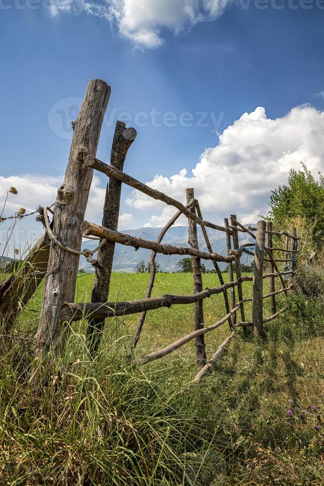 A handmade wooden fence made of thin rods. The old fence of tree trunks, rural landscape, nature wallpaper background. photo