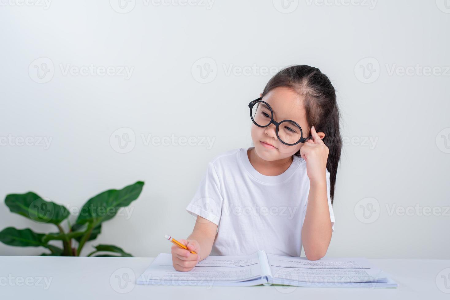 Portrait of little pupil writing at desk in  Student girl study doing test in primary school. Children writing notes in classroom. Education knowledge concept photo