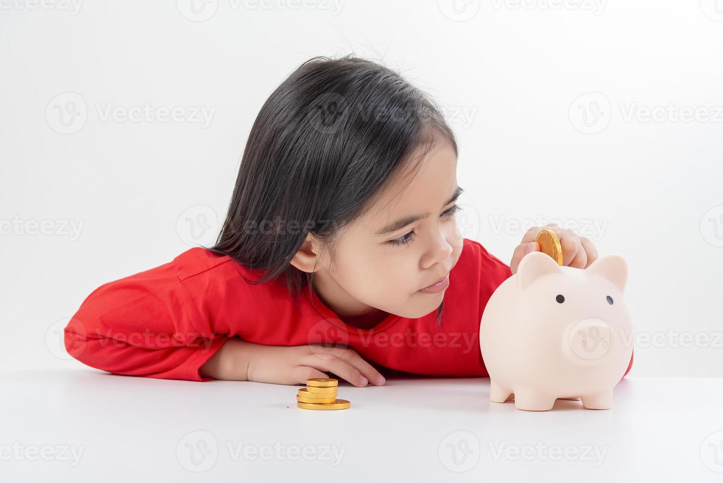 niña asiática ahorrando dinero en una alcancía, aprendiendo a ahorrar, los niños ahorran dinero para la educación futura. concepto de dinero, finanzas, seguros y personas foto