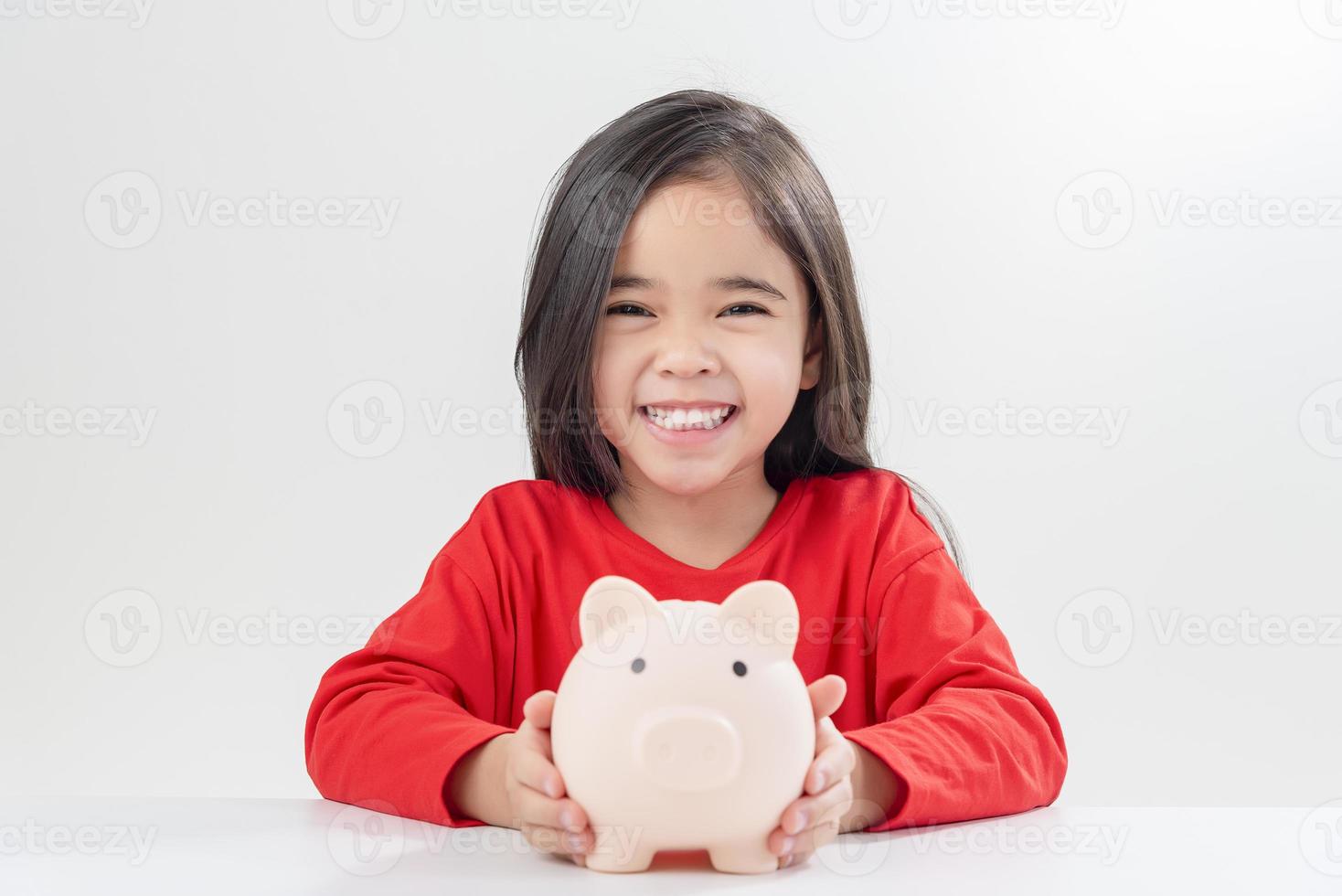 Little Asian girl saving money in a piggy bank, learning about saving, Kid save money for future education. Money, finances, insurance, and people concept photo