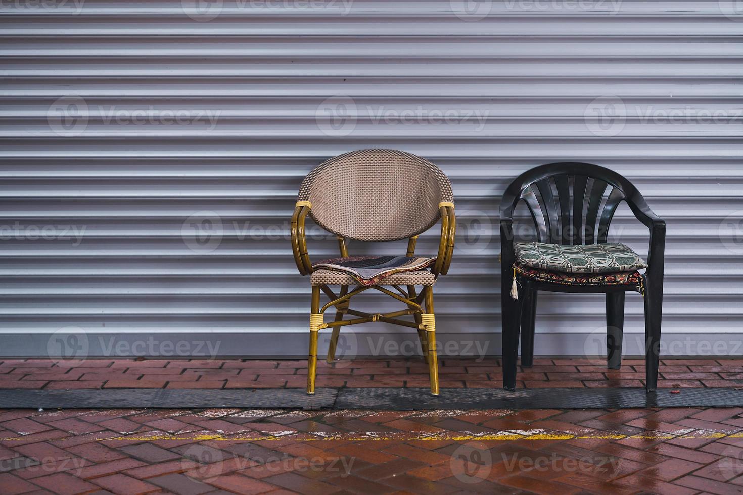 Chairs on the street near a roller-shuttered cafe, copy space. Street cafe in the rainy season photo