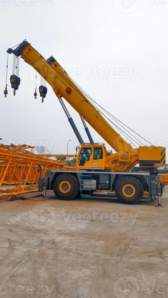 Yellow side view of yellow telescopic mobile crane boom up and park at the yard. photo