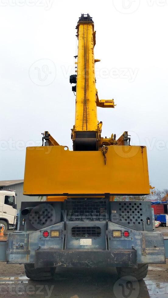 Rear view of yellow mobile crane boom up. photo