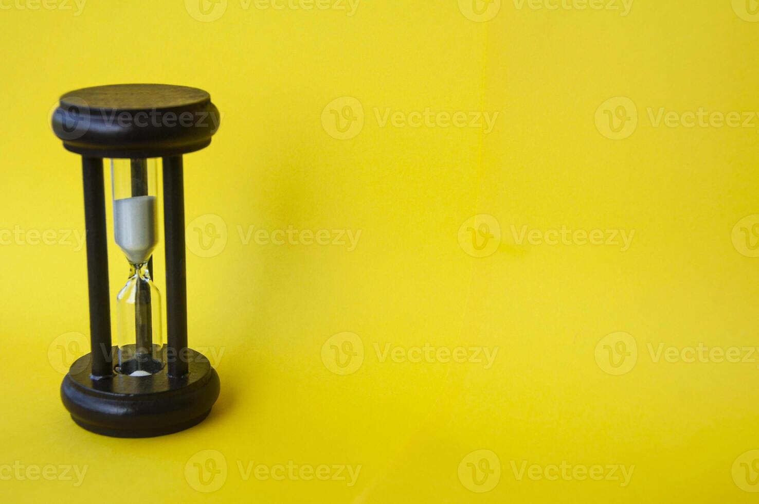 Minute glass isolated on yellow background. Copy space concept photo