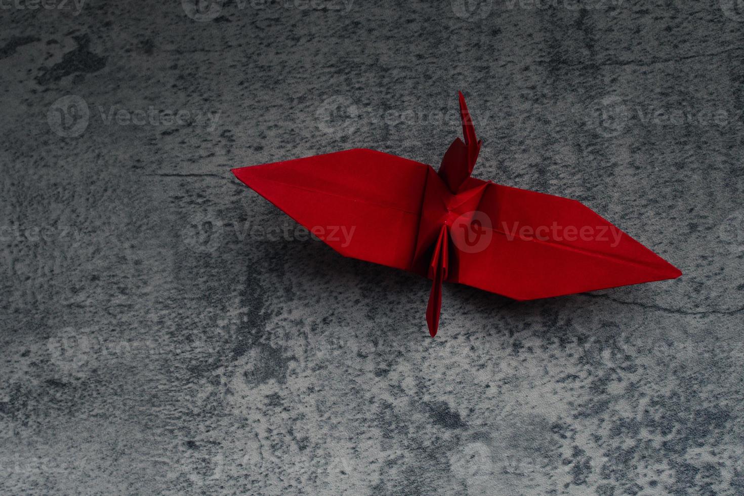 Red paper crane on gray background. Symbol of hope. photo