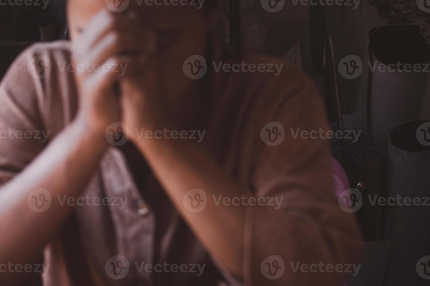 Blurred image of woman holding hands praying in vintage tones.For background. photo