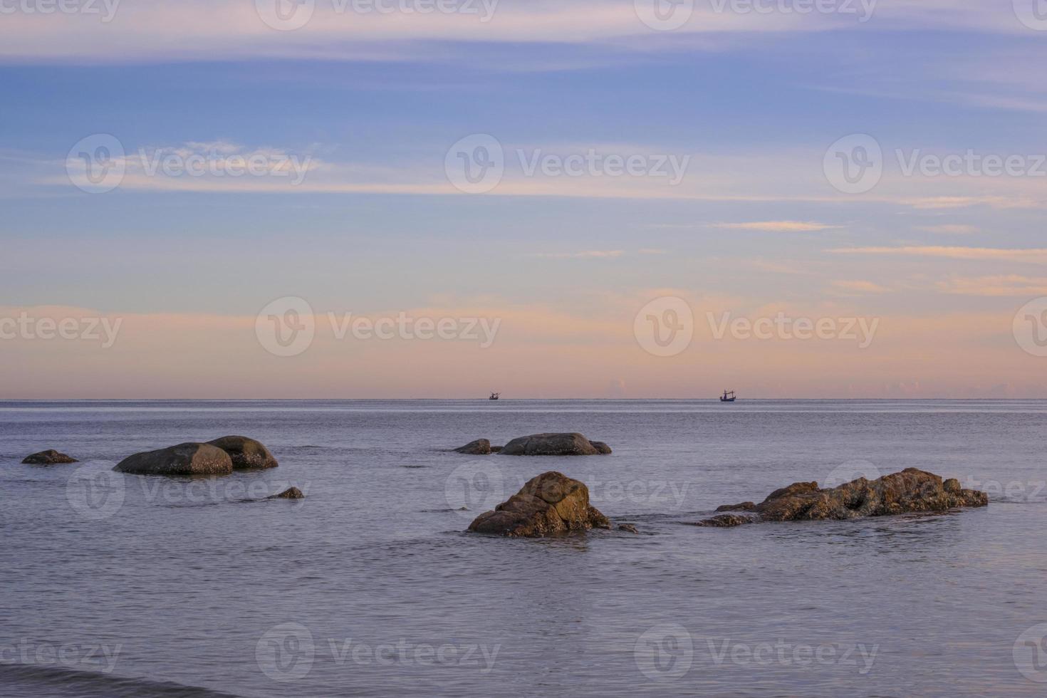 beautiful rock beach sunrise fresh sea breeze summer vacation. golden and blue sky with white clouds. photo