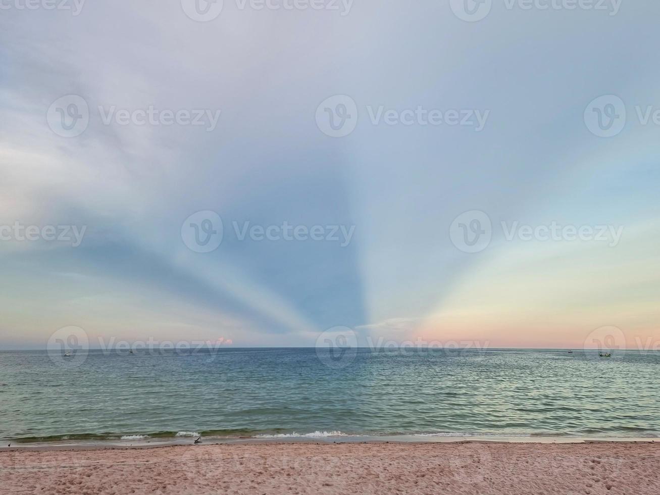 milagro sol luz puesta de sol triple forma en el cielo. playa de arena dorada cielo azul claro en tailandia foto