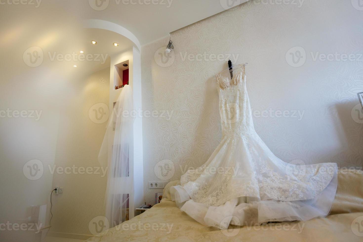 Beautiful wedding dress on hanger in room photo