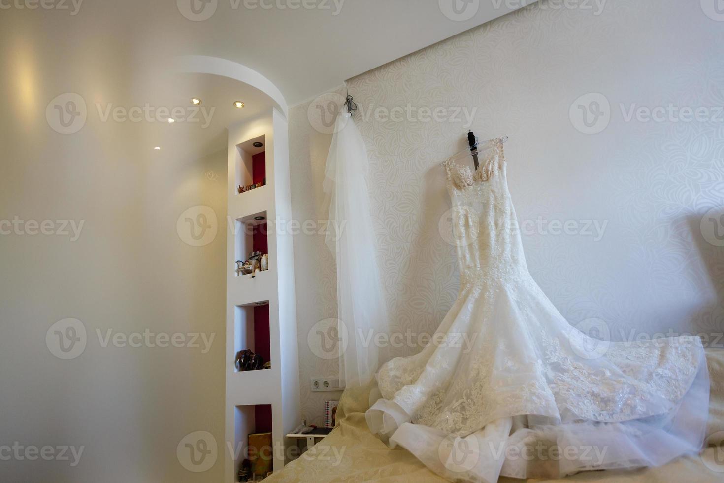 Beautiful wedding dress on hanger in room photo