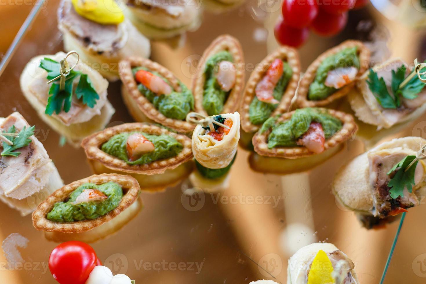 Beautifully decorated catering banquet table with burgers, profiteroles, salads and cold snacks. Variety of tasty delicious snacks on the table photo