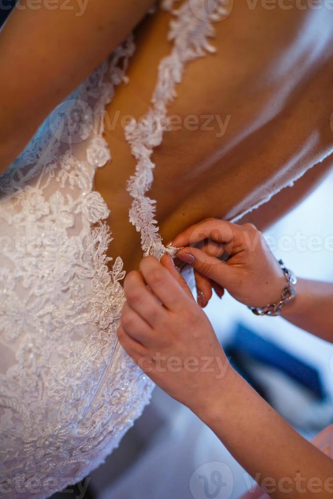 Bride putting on her white wedding dress photo