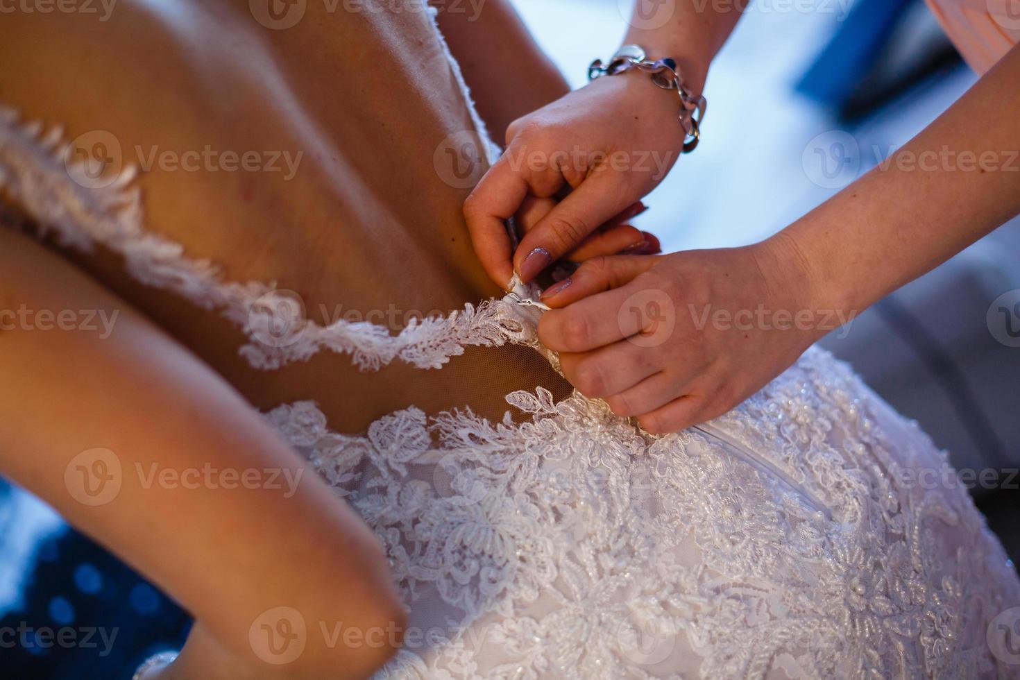 Bride putting on her white wedding dress photo