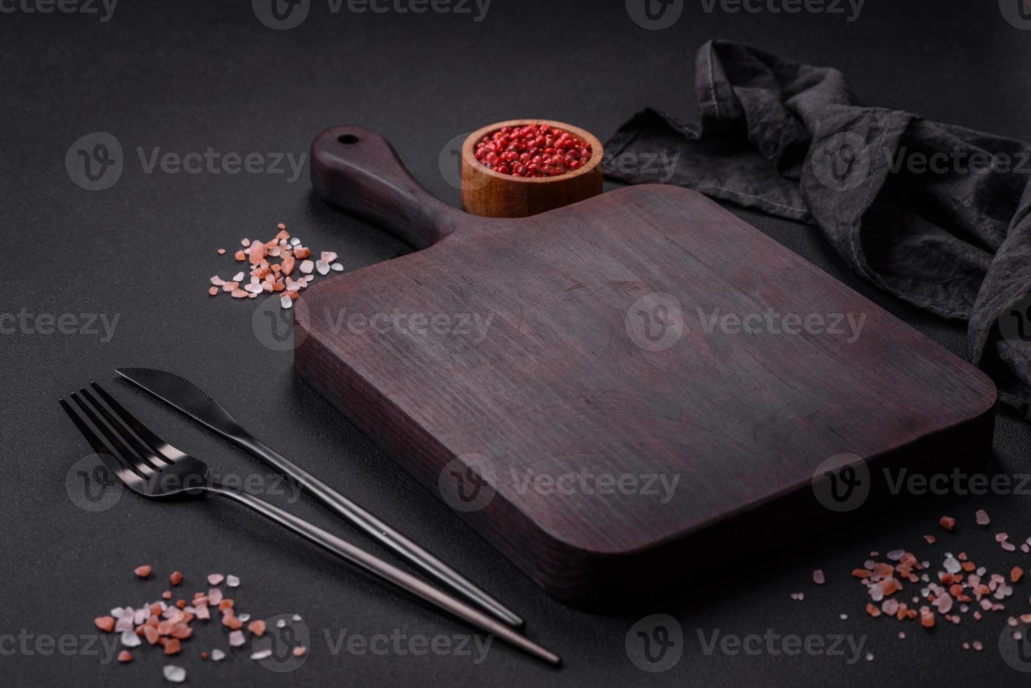 Empty wooden cutting board with spices and herbs photo