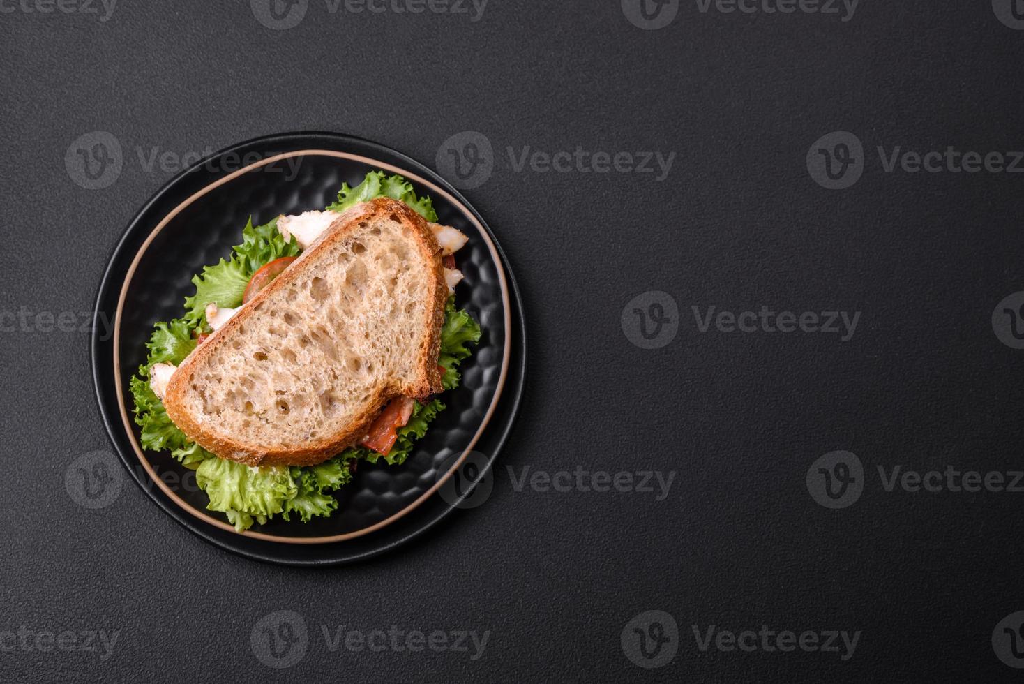 Fresh tasty sandwich with chicken, tomatoes and lettuce on a black plate photo