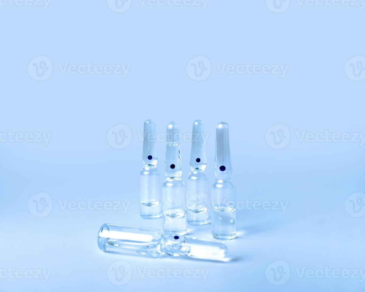 closed glass medical ampoules lie on a blue background. vessel for drugs photo