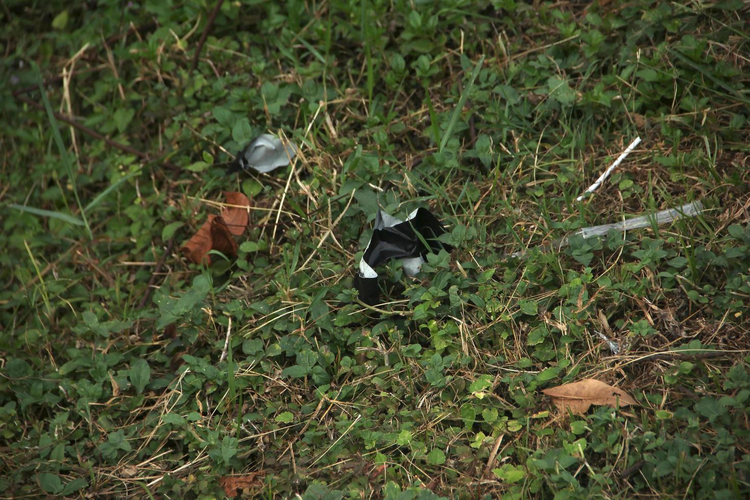 suelo con hierba y basura plástica a su alrededor. Área natural pública sucia. foto