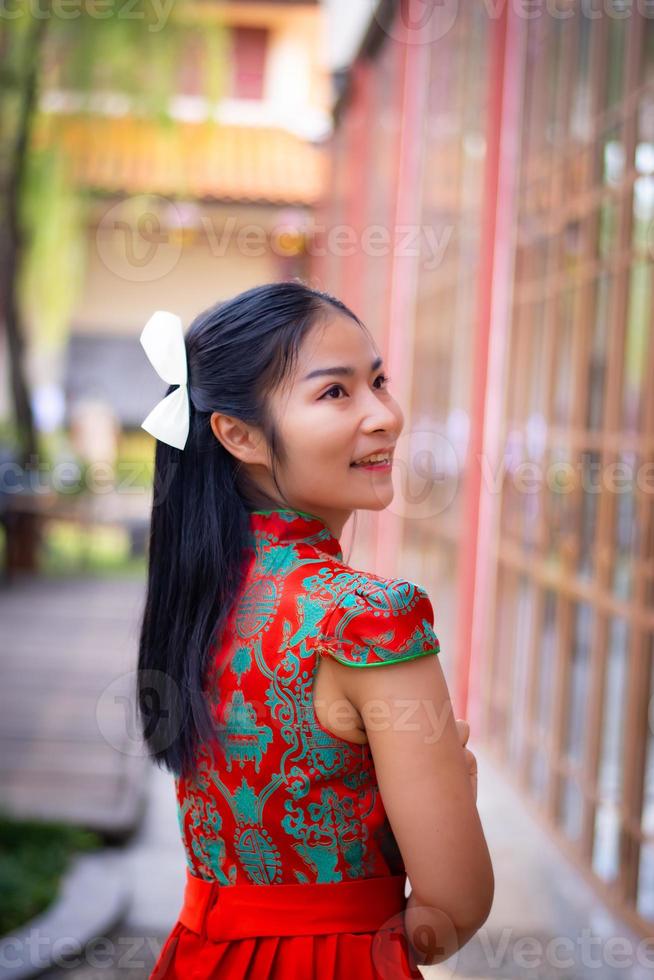 chica inteligente en vestido de color rojo estilo chiness año nuevo en cultura y fondo de templo chino público foto