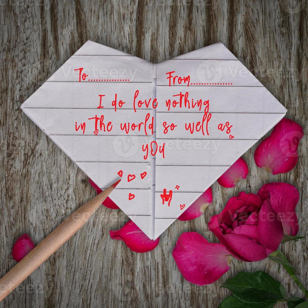 Love Quotes in Origami paper white heart, pencil and rose pink flower on wooden table background photo