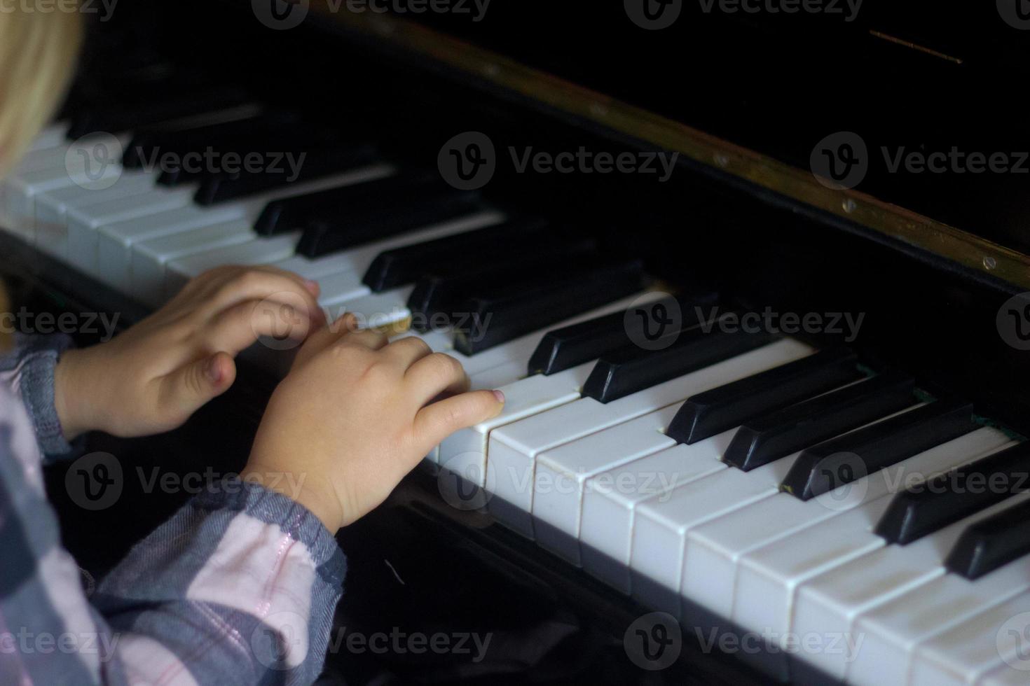 niña pequeña toca el piano, los niños manos en el teclado del piano de cerca, educación en el hogar, educación musical. niño talentoso en crecimiento. rutina diaria para niños pequeños, vista lateral de las manos y el piano de los niños foto