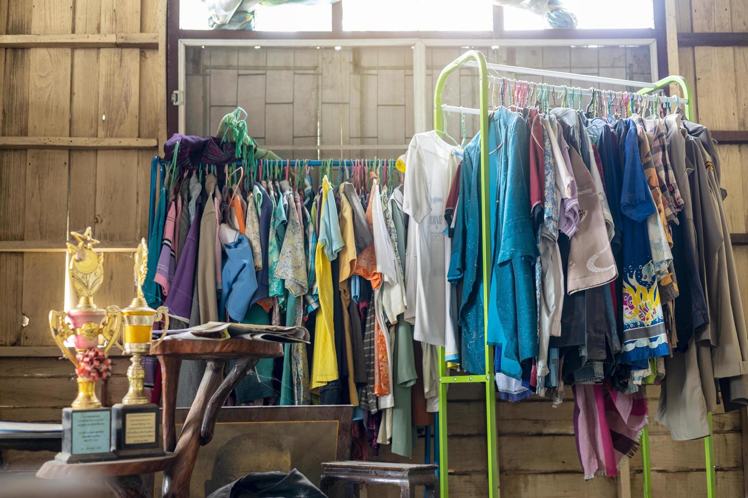 Colorful old clothes are hanging disorderly on iron railings near the cluttered things. photo