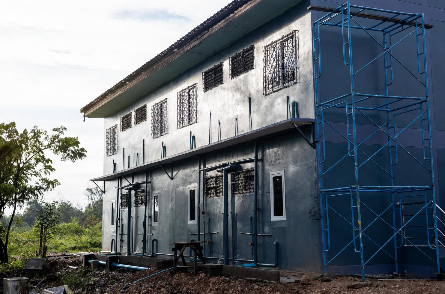 A low angle view of a gray condominium renovated using scaffolding. photo