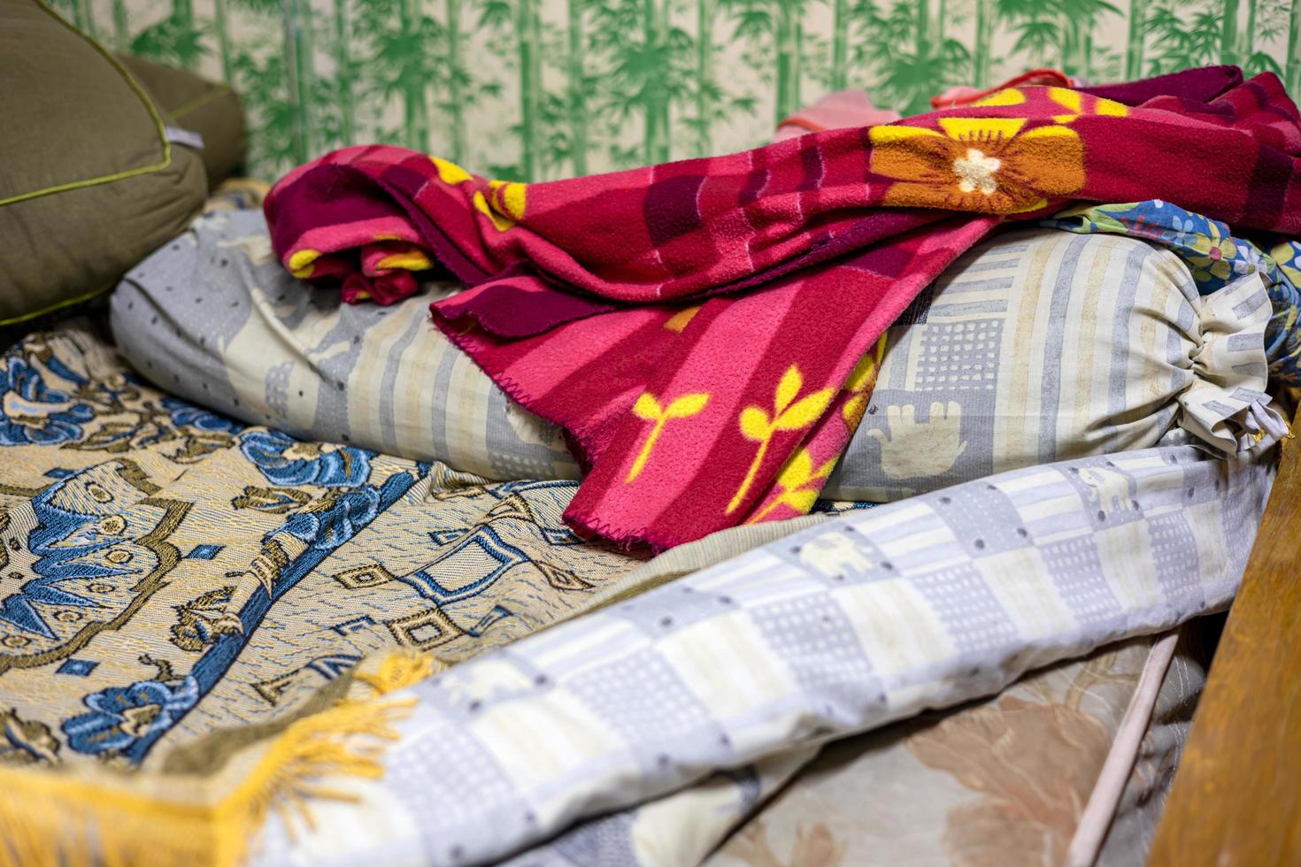 Close-up view of a red floral blanket lying on a dirty bolster. photo