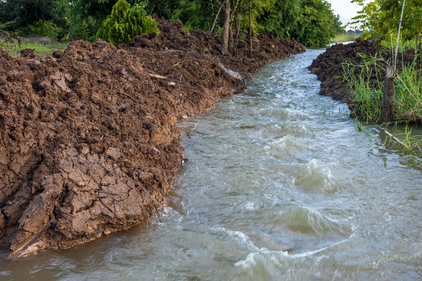 The view of the water rushing through the mounds of soil that have been dug up. photo