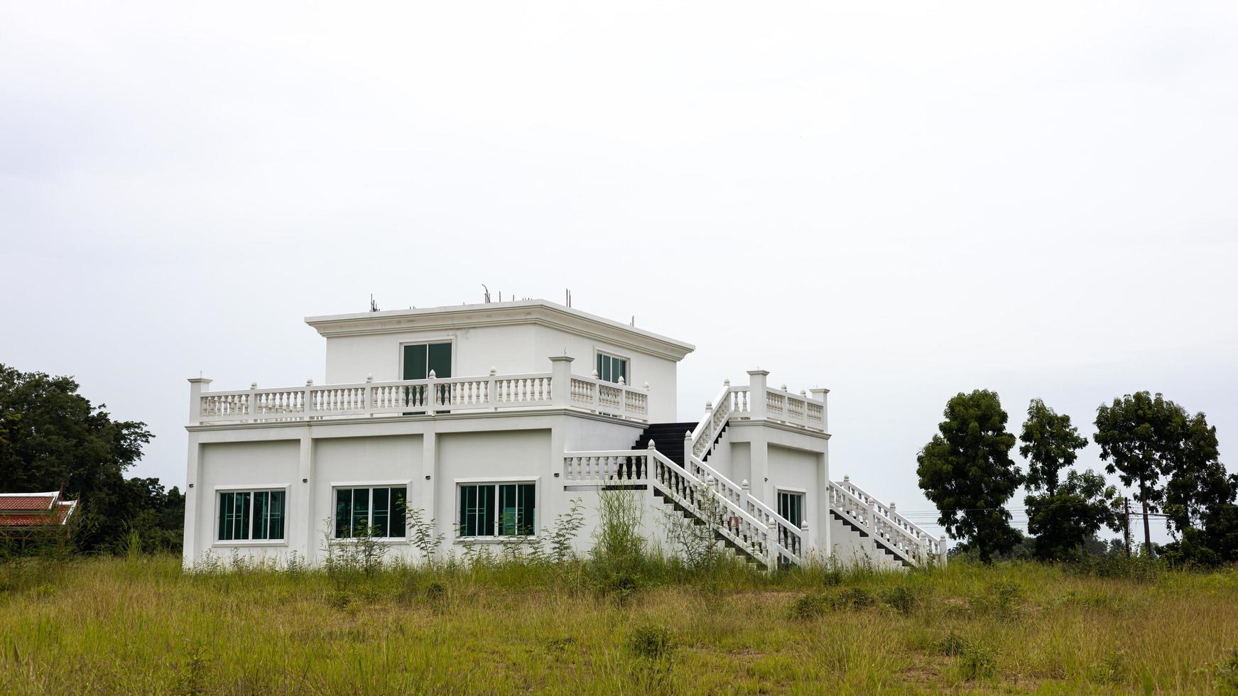 A view of a large, unfinished old abandoned white concrete building mounted on a ground floor filled. photo