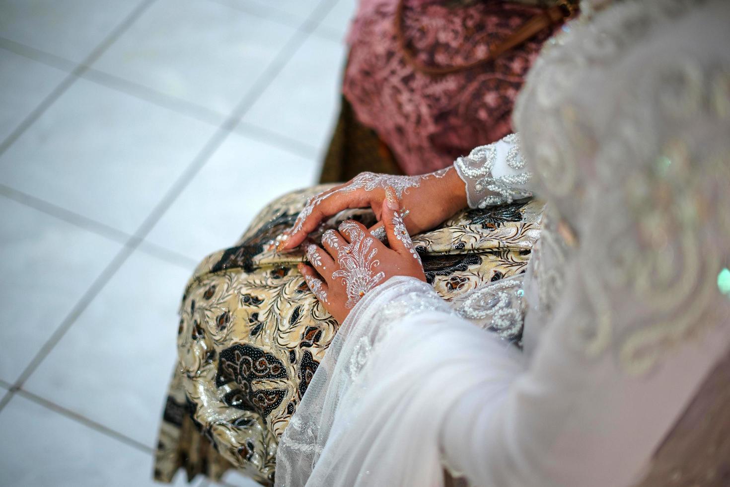 hermosa novia sosteniendo su mano mientras usa un vestido de novia en una ceremonia de boda tradicional en indonesia foto