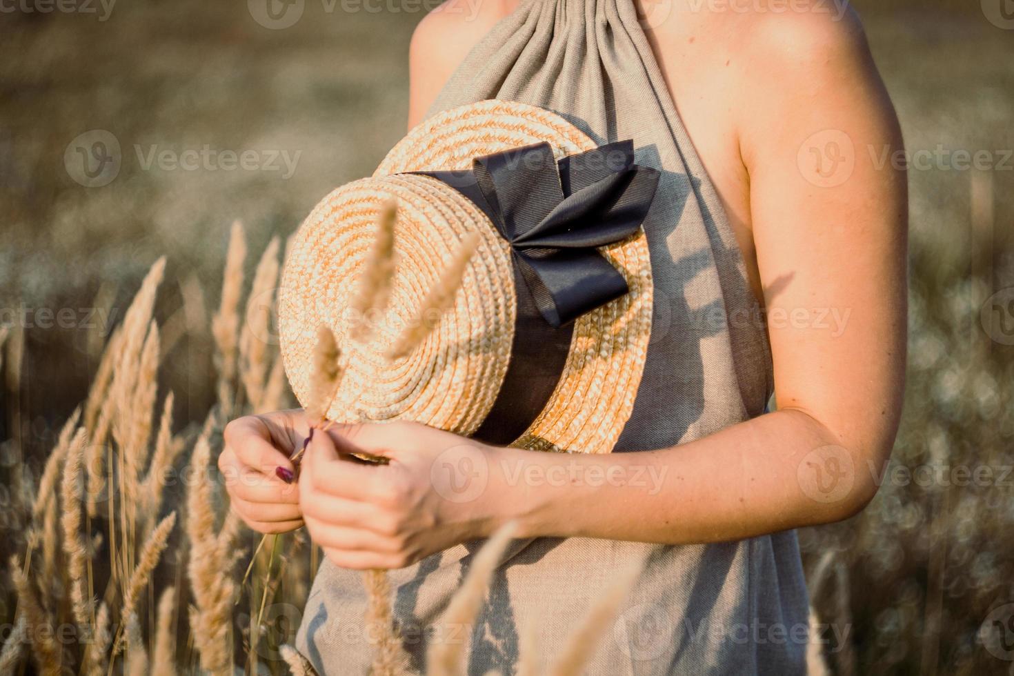 Close up pretty female hands holding straw hat with ribbon concept photo