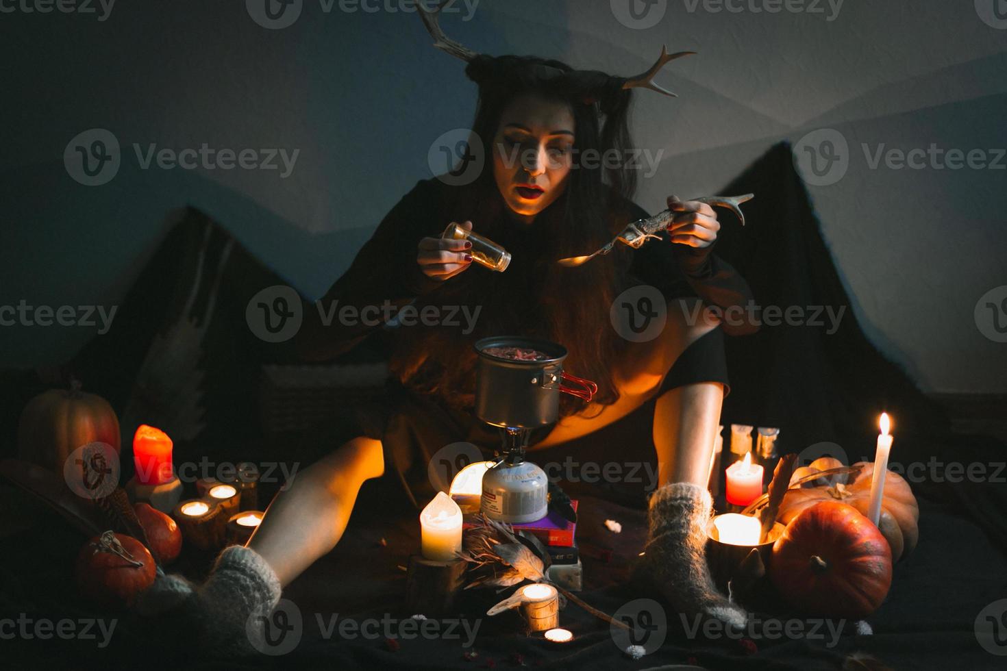 Close up female shaman with horns sprinkling spices into pot portrait picture photo