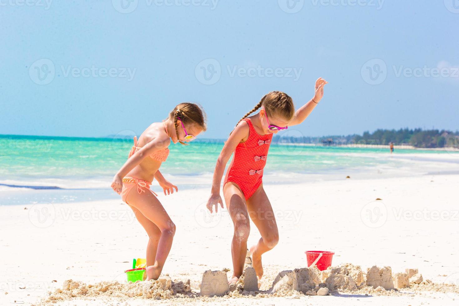 Adorable little girls during summer vacation. Kids playing with beach toys on the white beach photo
