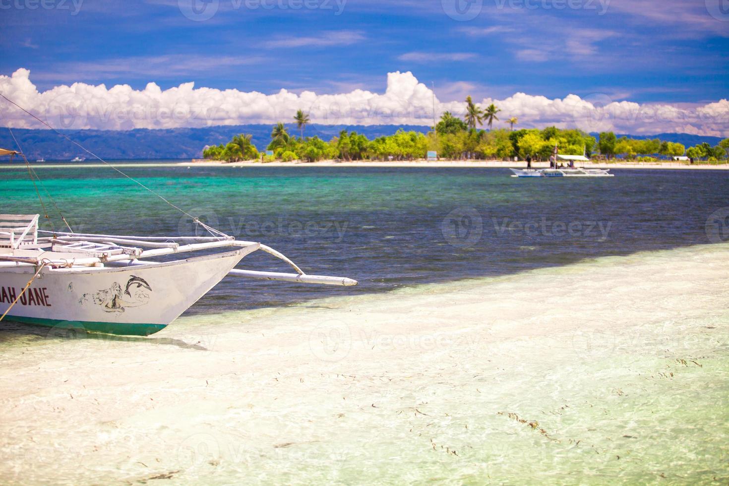 Small boat on white sandy tropical beach photo